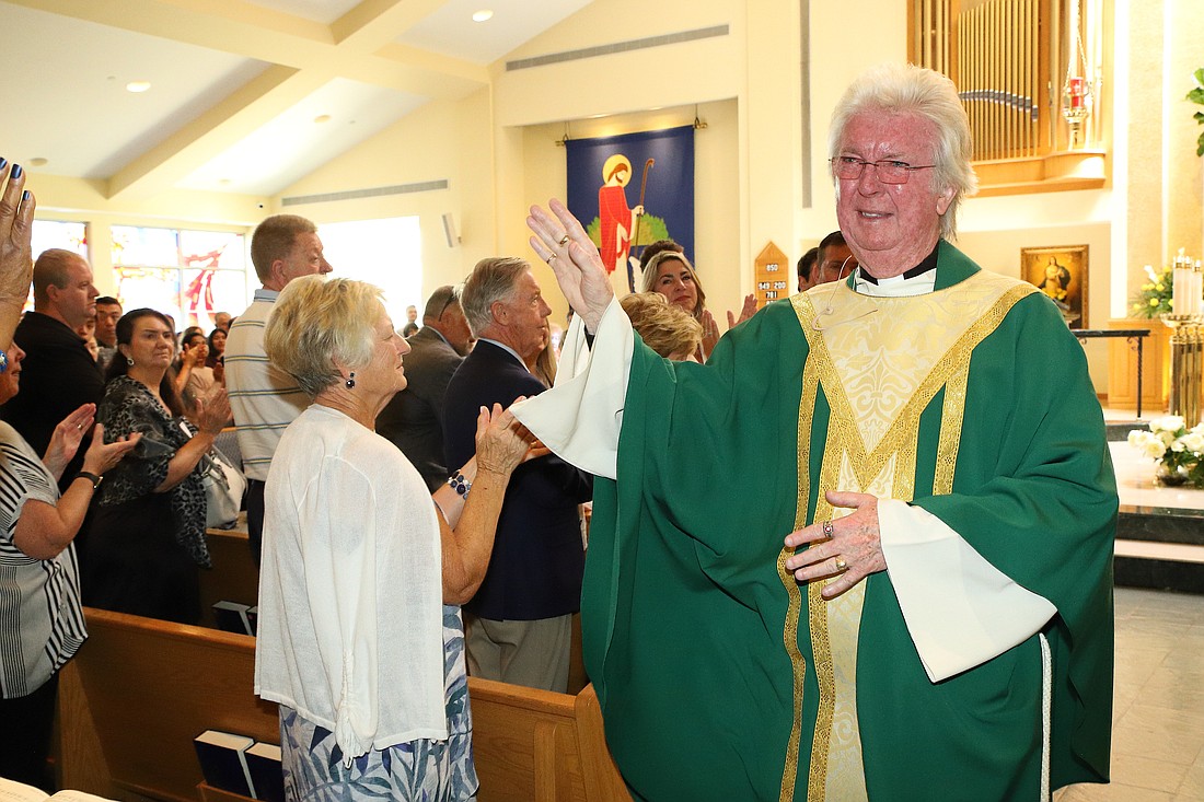Father Timothy J. Capewell waves as parishioners of St. David the King, 
Princeton Junction, applaud following his final Mass as pastor June 25. 
John Batkowski photos