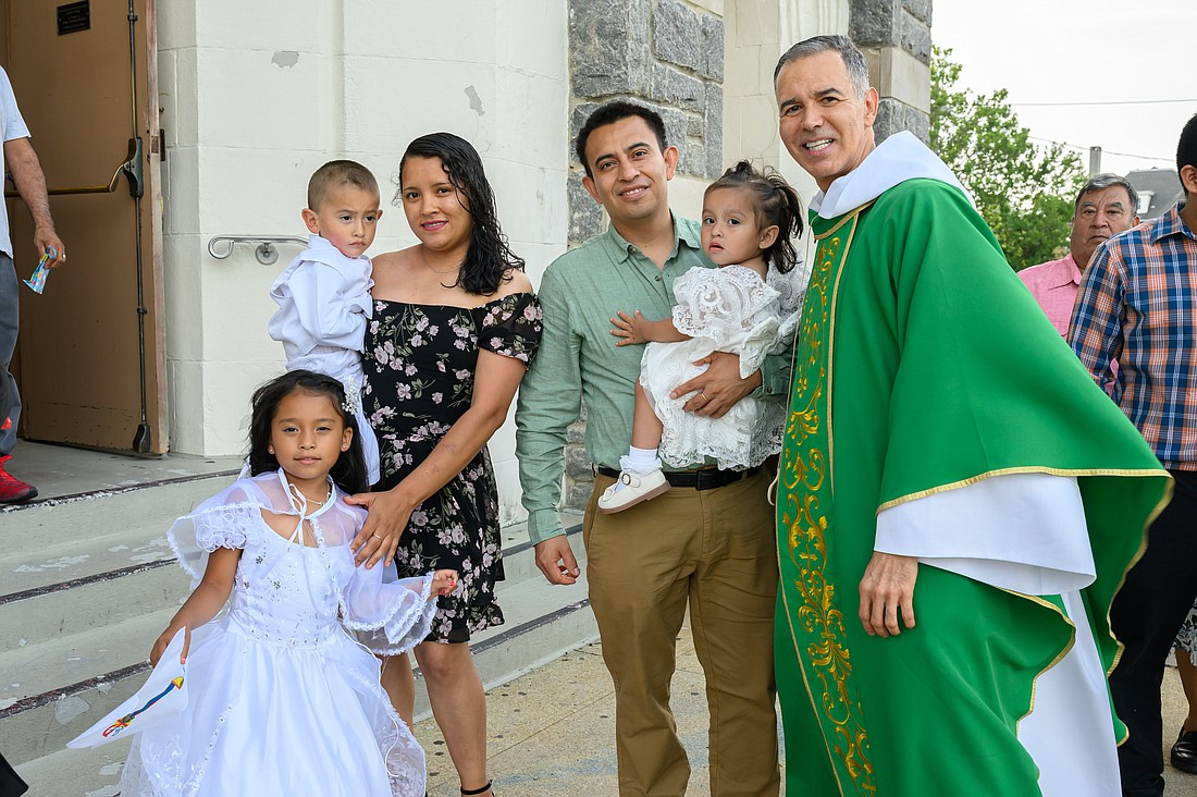 Father Diaz poses for a photo July 2 with a parish family outside Our Lady, Star of the Sea Church, Long Branch. Mike Ehrmann photo
