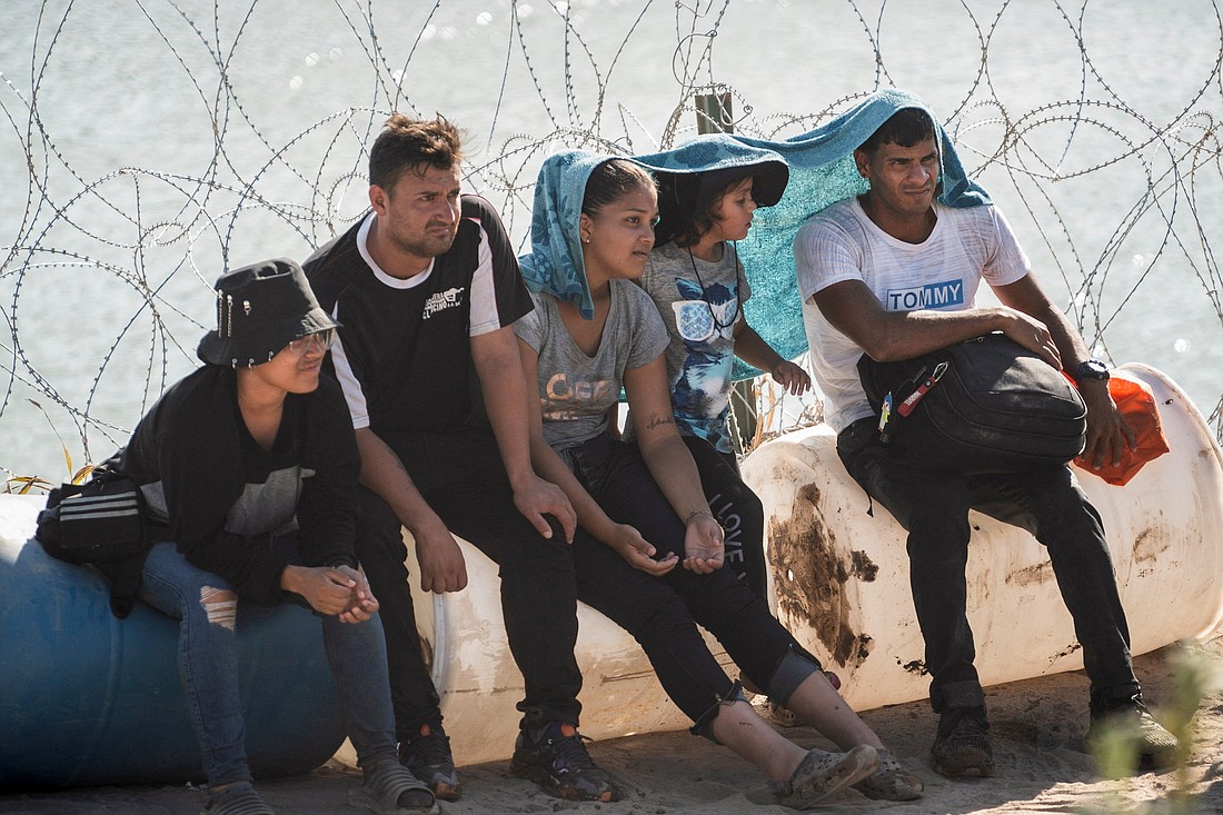 Asylum-seeking migrants sit by concertina wire fence while waiting to be transported by U.S. law enforcement officers after crossing the Rio Grande river into the U.S. from Mexico in Eagle Pass, Texas, July 24, 2023. (OSV News photo/Go Nakamura, Reuters)