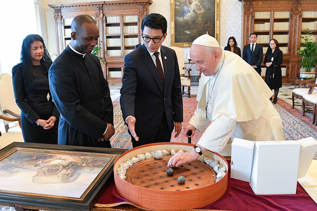 Pope Francis checks out one of the large marbles on a Madagascar Solitaire board given to him by President Andry Rajoelina of Madagascar during a meeting in the library of the Apostolic Palace at the Vatican Aug. 17, 2023. (CNS photo/Vatican Media)