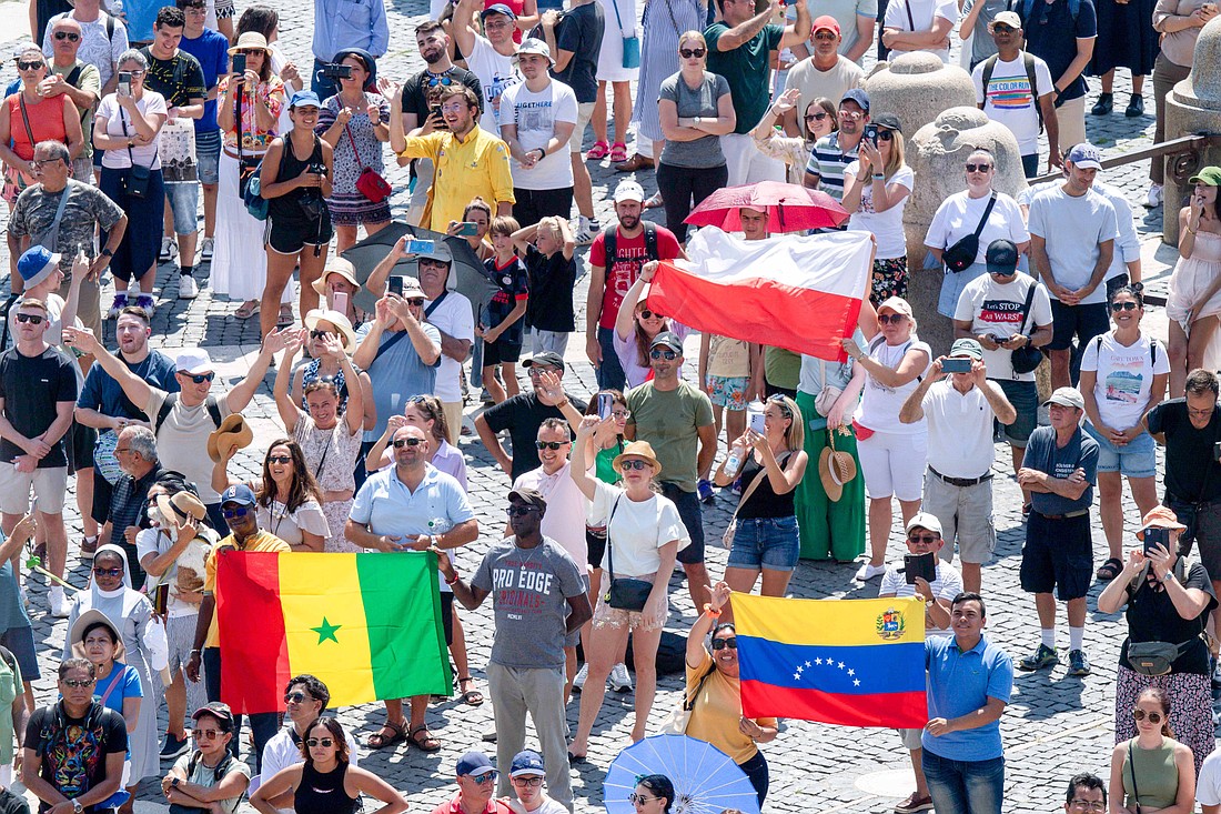 Visitantes ondean banderas de Polonia, Senegal y Venezuela mientras se reúnen en la Plaza de San Pedro del Vaticano para rezar el Ángelus con el Papa Francisco el 20 de agosto de 2023. (Foto CNS/Vatican Media)