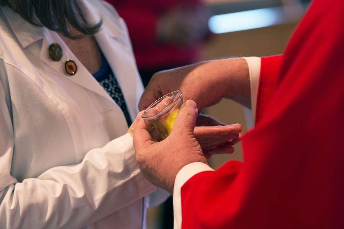 A healthcare worker's hands are blessed during a White Mass in this Monitor file photo.