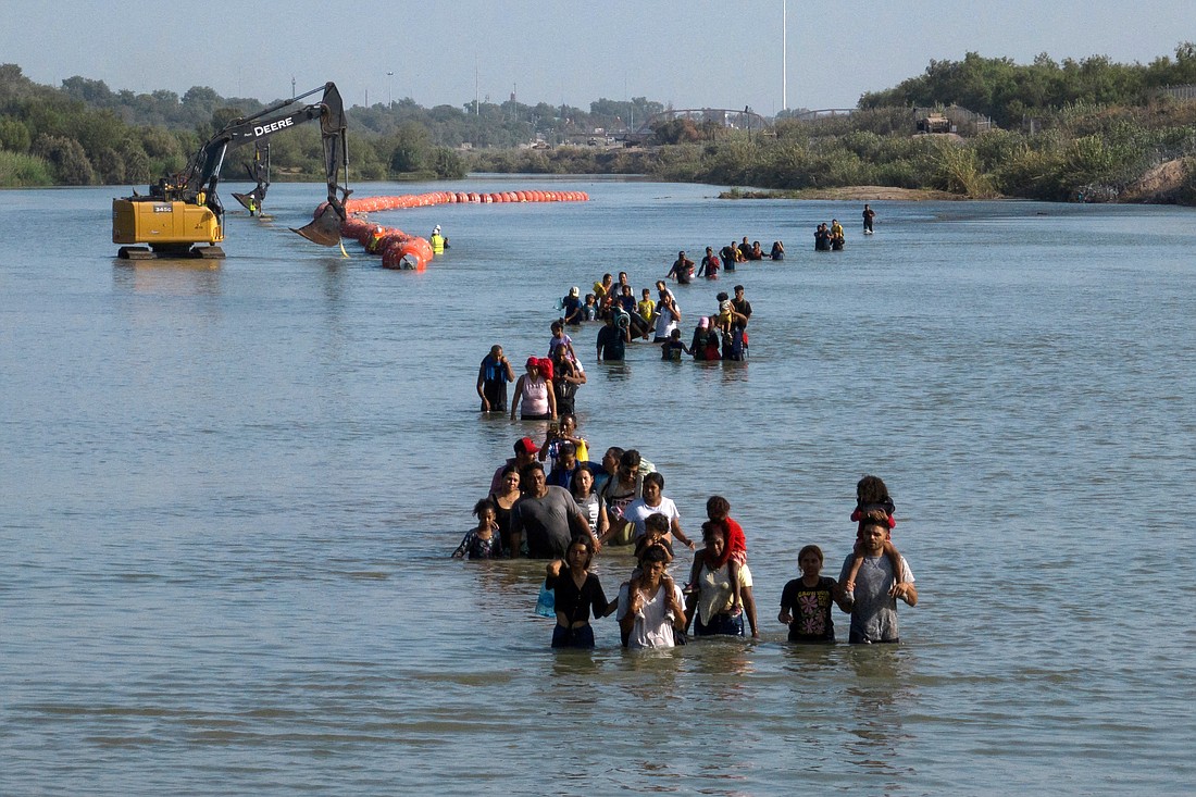 Migrants wade past buoys July 27, 2023, that were constructed to deter migrants attempting to cross the Rio Grande from Mexico into Eagle Pass, Texas. A federal judge ordered Texas Sept. 6 to remove the floating barriers and prohibited the state from adding or reinstalling additional buoys. (OSV News photo/Adrees Latif, Reuters)
