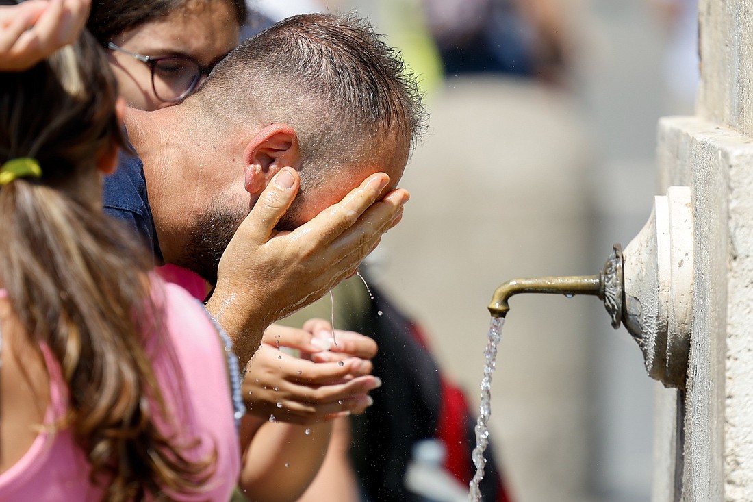 A visitor cools off by splashing water over his face at one of the drinking fountains in St. Peter's Square at the Vatican Aug. 17, 2023. (CNS photo/Lola Gomez)