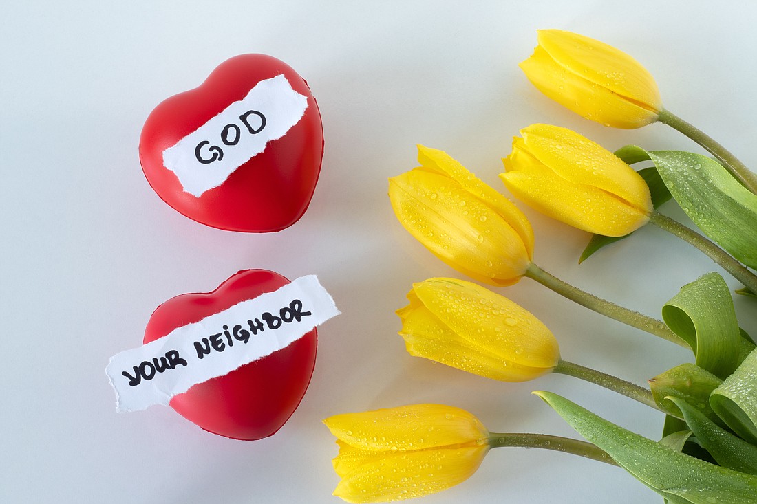 Love God and your neighbor, handwritten text, red hearts, and yellow tulips on white. Top view. Christian faith, obedience to Jesus Christ, the greatest commandment, biblical concept.