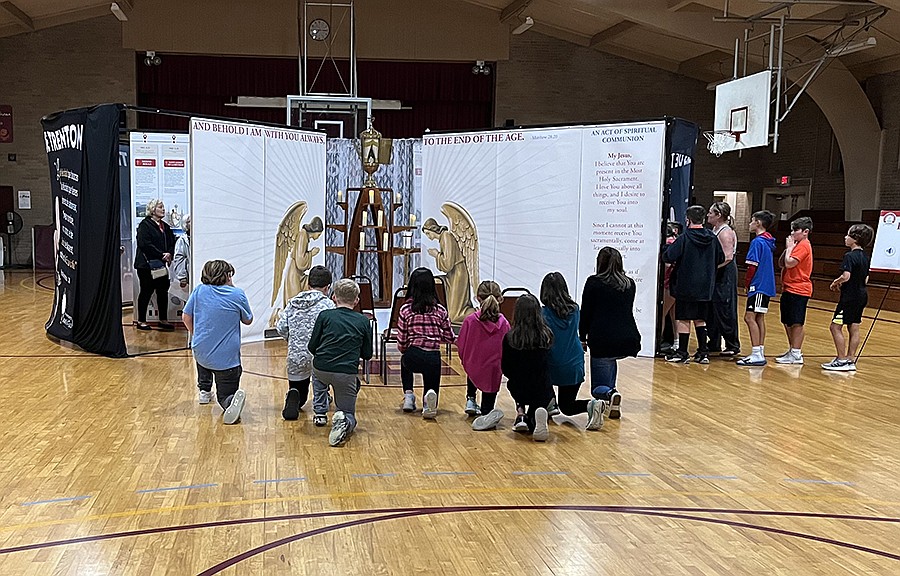 Children in the religious education program of Sacred Heart Parish, Riverton, genuflect before the Eucharist as they visit the Eucharistic Miracles exhibit in the parish family center gym. Photo courtesy of Fran Stinsman