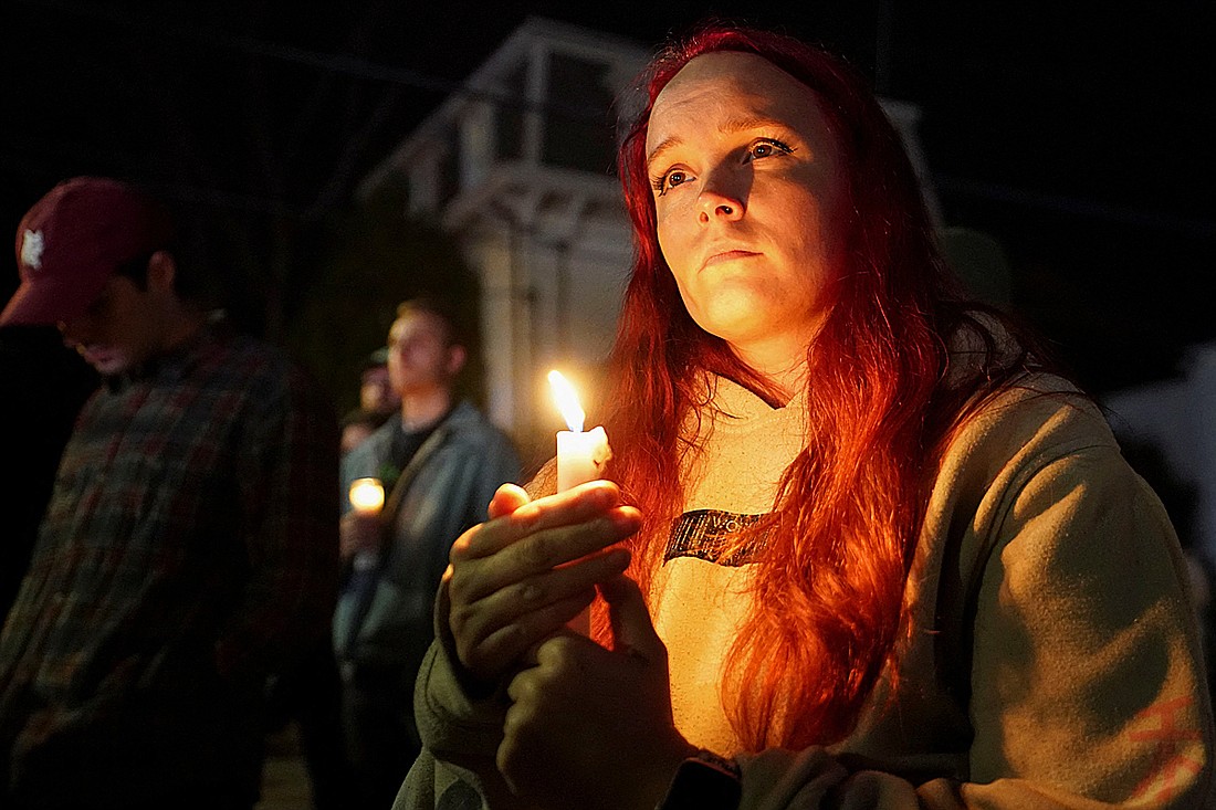 A woman holds a candle outside the Basilica of Sts. Peter and Paul in Lewiston, Maine, Oct. 29, 2023, during a vigil for the victims of a deadly mass shooting. Robert Card, who later took his own life, shot and killed 18 people and injured 13 others at a restaurant and a bowling alley in Lewiston Oct. 25. OSV News photo/Kevin Lamarque, Reuters