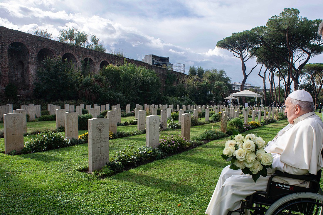 Pope Francis holds a bouquet of white roses as he visits the graves of members of Commonwealth military units who died during and immediately after World War II and now rest in the Rome War Cemetery where the pope celebrated Mass Nov. 2, 2023, the feast of All Souls. (CNS photo/Vatican Media)
