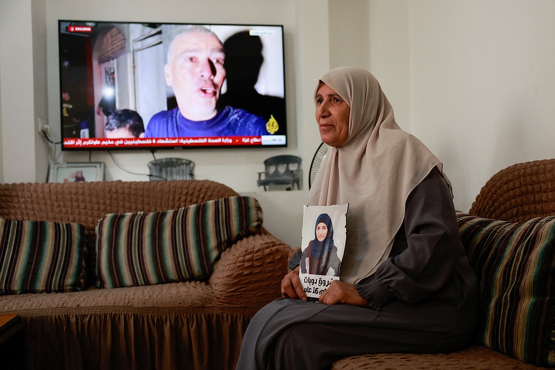 Sameera Dwayyat, the mother of Shorouq Dwayyat, 26, a female Palestinian prisoner serving a 16-year sentence, holds a picture of her daughter in Jerusalem, Nov. 22, 2023, as news updates on a deal to exchange Hamas hostages for Palestinian prisoners held by Israel appear on a television, amid the ongoing conflict between Israel and the Palestinian Islamist group Hamas. (OSV News photo/Ammar Awad, Reuters)