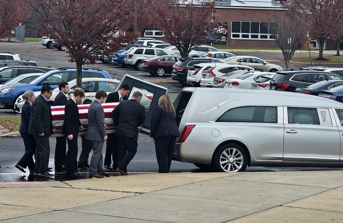 Deacon Wilson's casket, which is draped with the American flag, is placed in the hearse after the funeral Mass. Deacon Wilson was laid to rest in St. Mary Cemetery, Hamilton. Mary Stadnyk photo