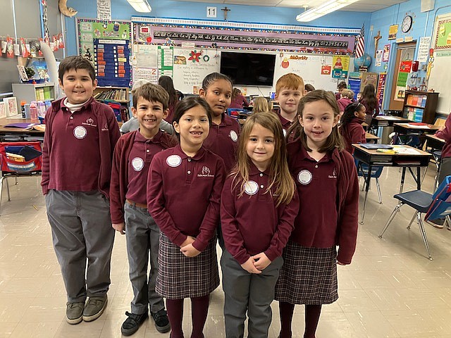 Second grade students from St. Ann School, Lawrenceville, proudly wear their Giving Tuesday stickers detailing how they are making a difference in their school, their homes and in the world. Facebook photo