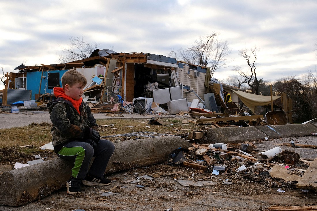 A child sits on a downed pole outside a destroyed home in Clarksville, Tenn., Dec. 10, 2023, a day after a tornado swept through the town. (OSV News photo/Kevin Wurm, Reuters)