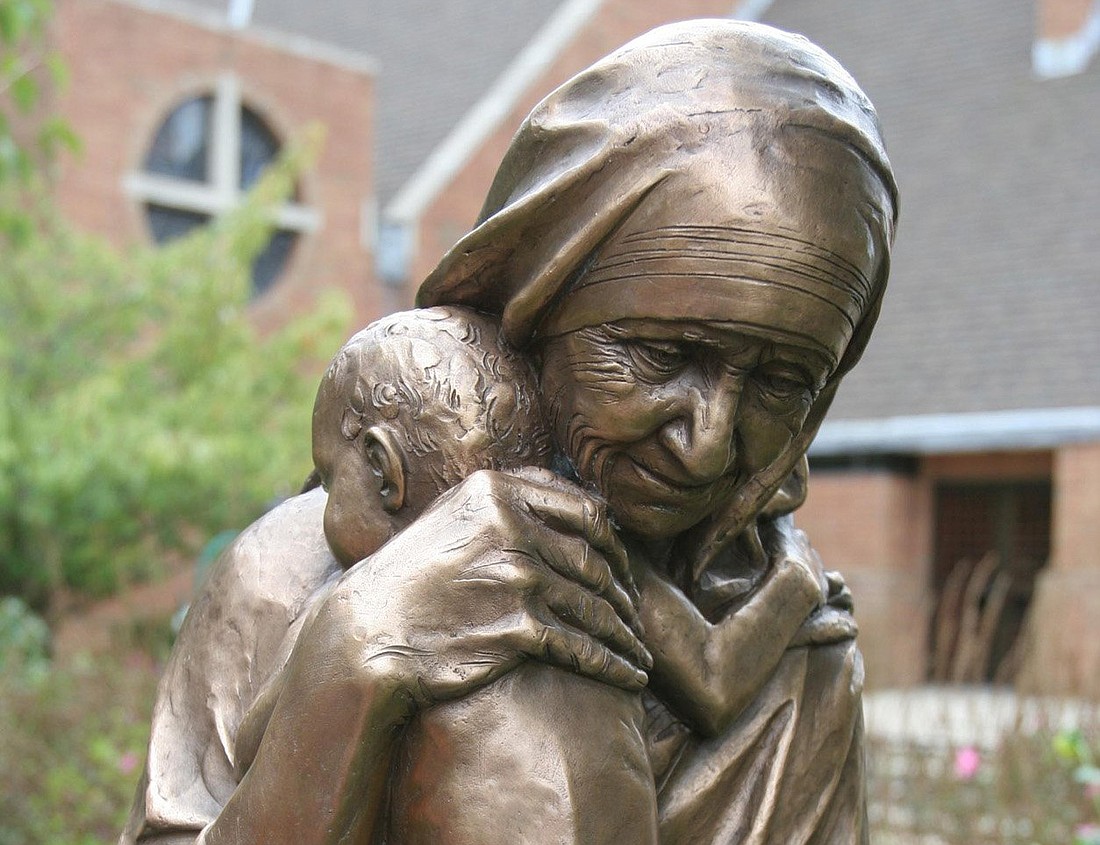A bronze statue of St. Teresa of Kolkata, cradling a child, is pictured in a file photo overlooking a garden at Our Lady of Lourdes Church in Massapequa Park, N.Y. The statue was donated by the Knights of Columbus. OSV News photo/CNS file, Gregory A. Shemitz, Long Island Catholic