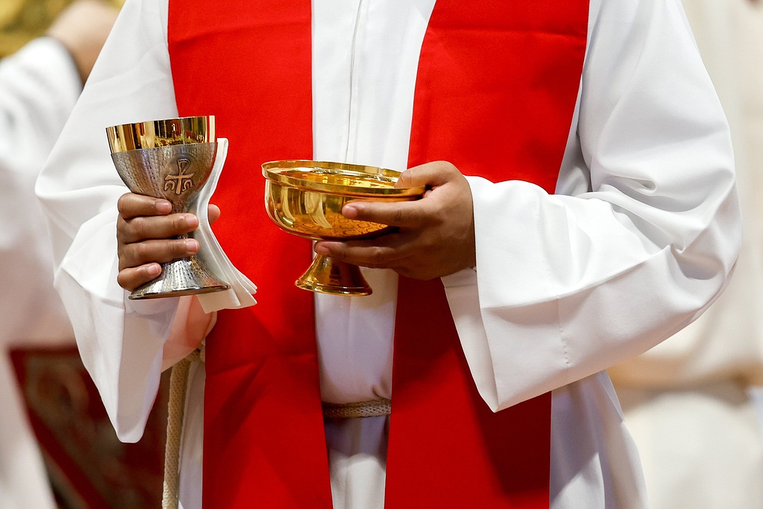 This photo illustration shows a priest preparing to distribute Communion during Mass in St. Peter's Basilica at the Vatican June 29, 2023. (CNS photo/Lola Gomez)