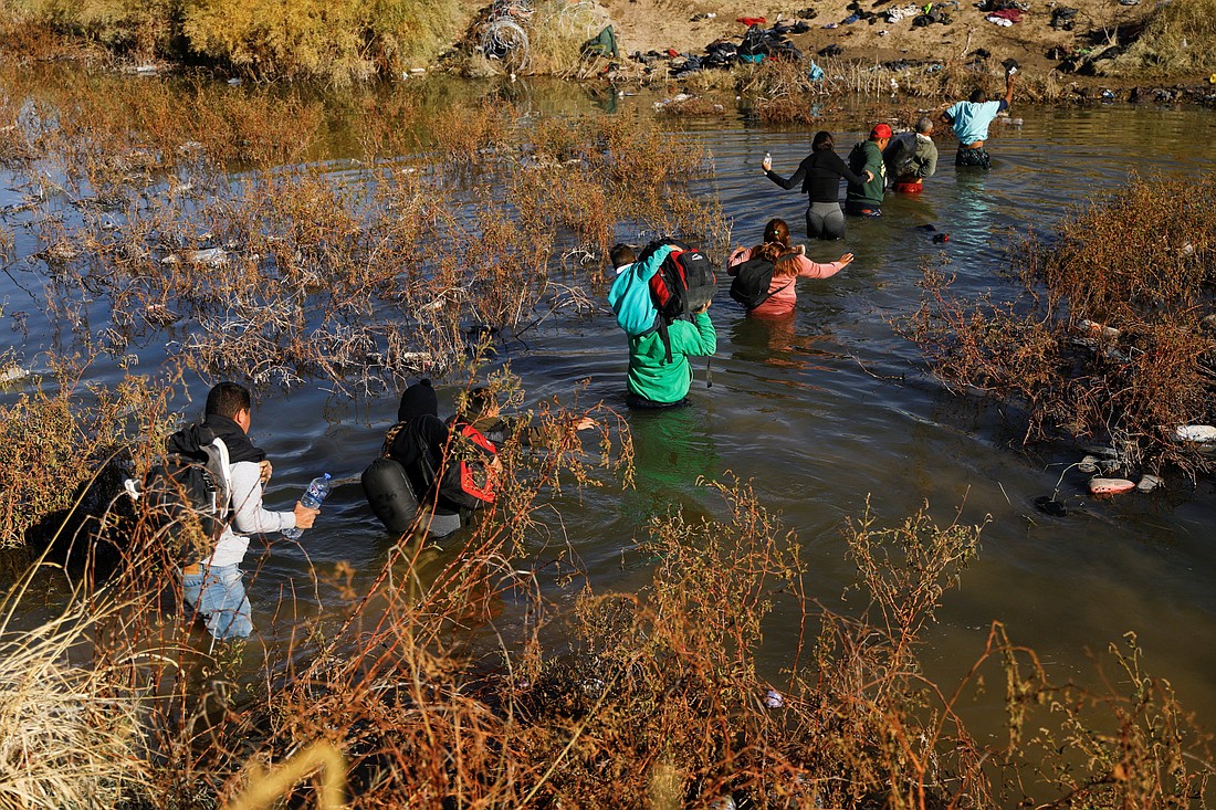 Migrants cross the Rio Bravo, the border between the United States and Mexico, with the intention of turning themselves over to U.S. Border Patrol agents to request asylum, as seen from Ciudad Juarez, Mexico on Dec. 18, 2023. Texas Gov. Greg Abbott signed a measure the same day that gives law enforcement officials the power to arrest immigrants entering the state illegally from Mexico. (OSV News photo/Jose Luis Gonzalez, Reuters)