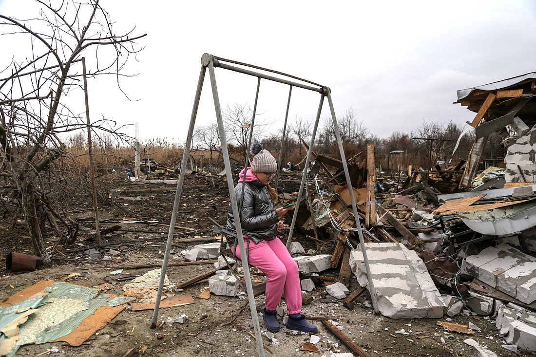 A girl uses her mobile phone Jan. 1, 2024, while she sits on a swing in Odesa, Ukraine, at a compound of residential houses heavily damaged during a Russian drone strike. (OSV News photo/Serhii Smolientsev, Reuters)