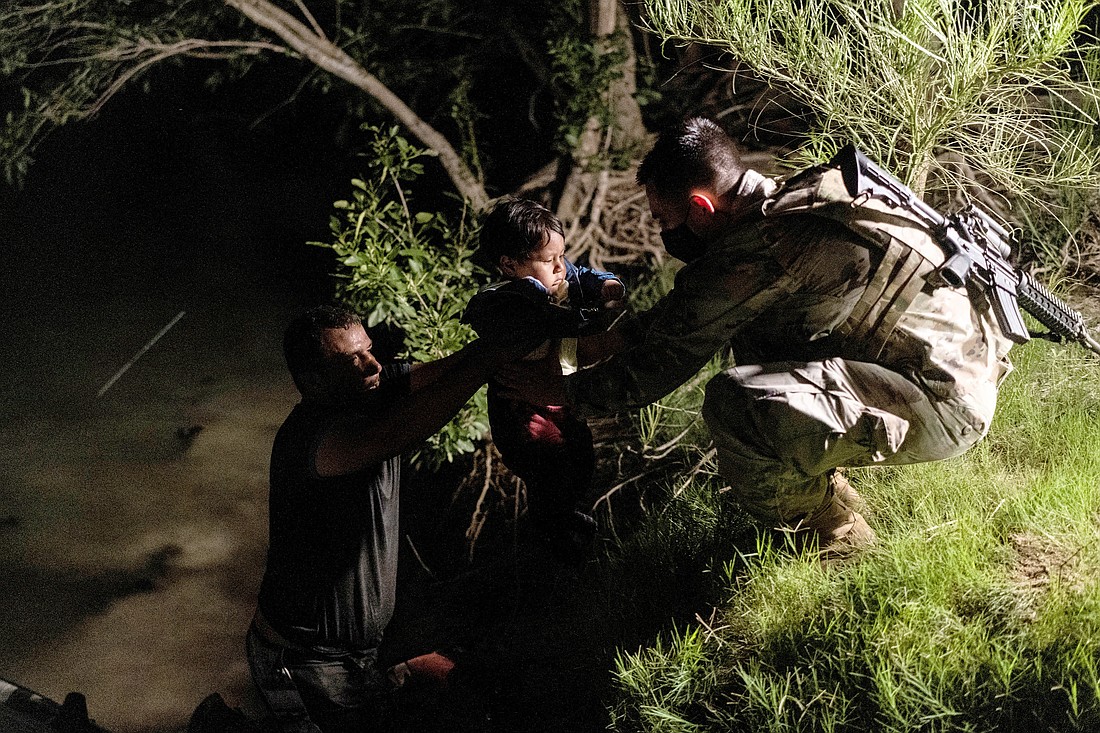 A human trafficker passes an asylum-seeking migrant child to a member of the U.S. National Guard in Roma, Texas, after crossing the Rio Grande into the United States from Mexico June 10, 2021. Along the nearly 7,000-mile-long U.S.-Mexico border, U.S. Customs and Border Protection Officers and Border Patrol agents work to identify potential trafficking victims among those seeking to enter the U.S., according to the CBP website. (OSV News photo/Go Nakamura, Reuters)