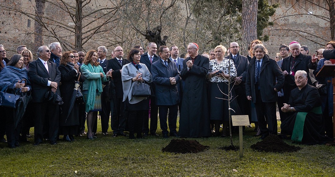 A group poses for a picture in the Vatican Gardens March 6, 2024, behind an apple tree planted to commemorate the Ulma family 80 years after their death on March 24, 1944, in Markowa, Poland, at the hands of German occupiers who killed the entire family for giving shelter to Jews in their house. Near the center is Cardinal Pietro Parolin, Vatican's secretary of state, with Wladyslaw Ortyl, marshall of Poland's Podkarpacie region, at left, and Grazyna Ignaczak -Bandych, chief of Cabinet to the president of Poland, at right. Also in attendance were several diplomats as well as people connected to the Ulma family's beatification process. (OSV News photo/courtesy Office of the Marshal of Podkarpacie)