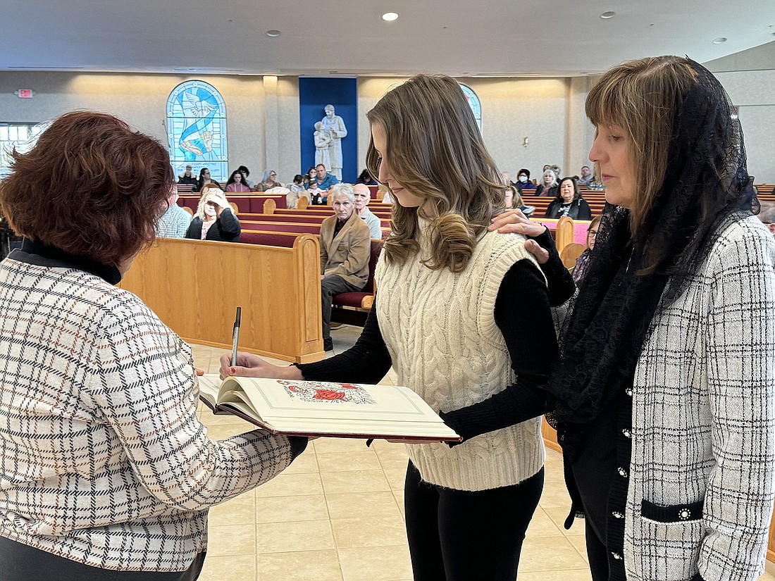 Lauren Paige Pellegrino, a catechumen in St. Pius X Parish, Forked River, signs the Book of the Elect during the parish’s Rite of Sending ceremony held Feb. 18. Marianne Hartman photo