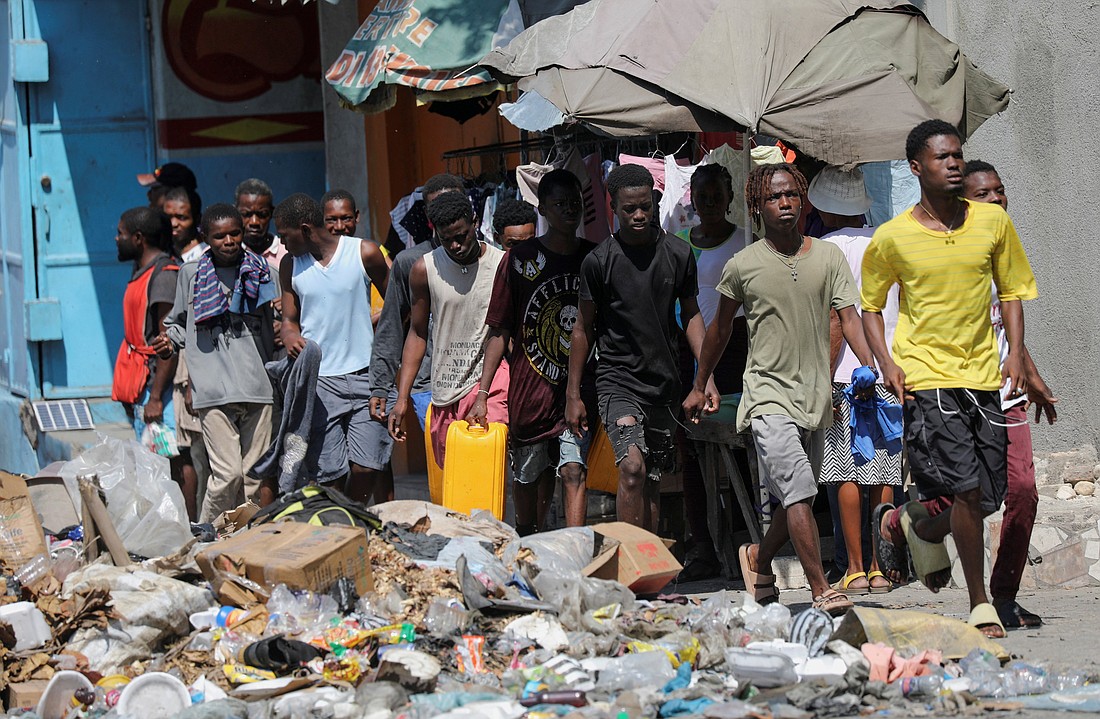 People wait in line amid trash along a street to collect water in buckets and containers after Haitian Prime Minister Ariel Henry pledged to step down following months of escalating gang violence, in Port-au-Prince, March 12, 2024. (OSV News photo/Ralph Tedy Erol, Reuters)