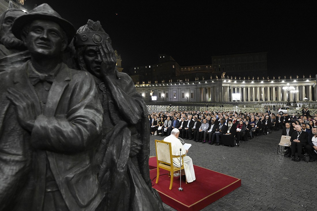 Pope Francis leads members of the assembly of the Synod of Bishops in praying for migrants and refugees in front of the statue, "Angels Unawares," in St. Peter's Square Oct. 19, 2023. The sculpture by Canadian Timothy Schmalz, depicts a boat with 140 figures of migrants from various historical periods and various nations. (CNS photo/Vatican Media)