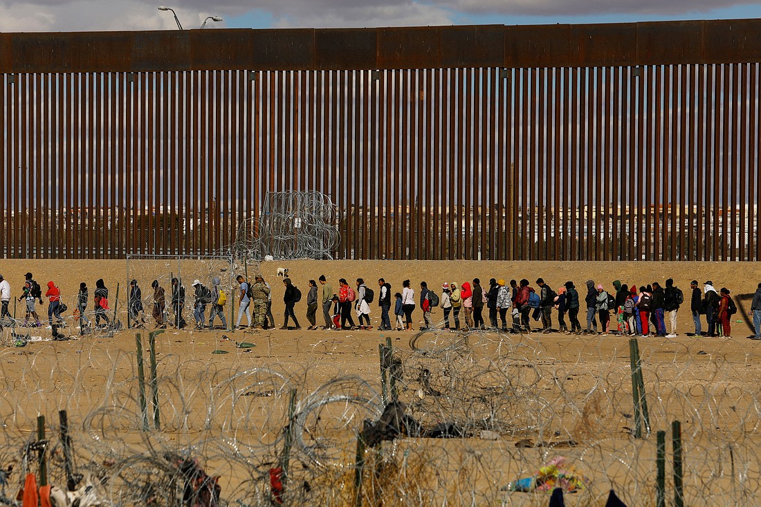 Migrants seeking asylum in the United States gather near the border wall Jan. 22, 2024, as seen from Ciudad Juarez, Mexico, after they crossed a razor wire fence and as members of the Texas National Guard stand guard. (OSV News photo/Jose Luis Gonzalez, Reuters)