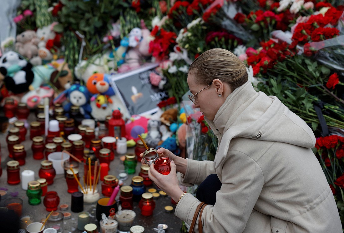 A woman lights a candle at a makeshift memorial March 24, 2024, outside the Crocus City Hall concert venue following a shooting incident, outside Moscow March 22. Assailants burst into the concert hall and sprayed the crowd with gunfire, killing over 130 people, injuring more than 100 and setting fire to the venue. (OSV News photo/Maxim Shemetov, Reuters)