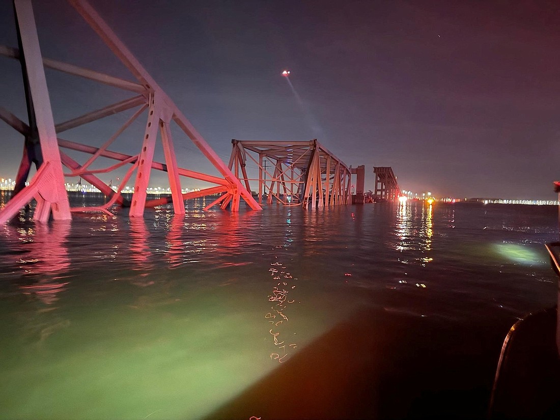 A U.S. Coast Guard helicopter hovers near the Francis Scott Key Bridge in Baltimore after the Dali cargo vessel crashed into it March 26, 2024, causing it to collapse. Andy Middleton, the director of the Archdiocese of Baltimore's Apostleship of the Sea, said he had been in touch with a member of the crew just hours after the collision and that all aboard were safe and uninjured.  (OSV News photo/Baltimore City Fire Department Rescue Company handout via Reuters) NO ARCHIVES. MUST DISCARD 30 DAYS AFTER DOWNLOAD.