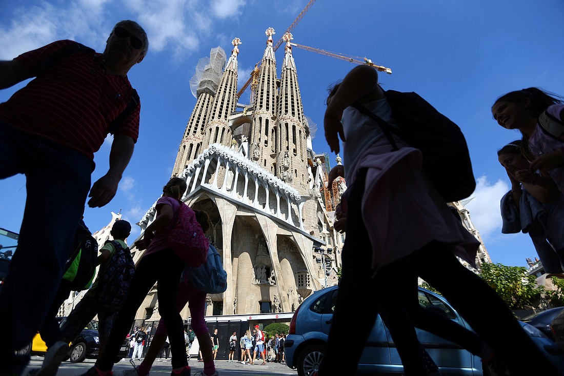 People walk near the Basilica of the Holy Family, or Sagrada Familia, in Barcelona, Spain, Oct. 11, 2017. After more than a century, construction of the basilica will be completed in 2026, the foundation overseeing the project announced March 20, 2024. (OSV News photo/Ivan Alvarado, Reuters)