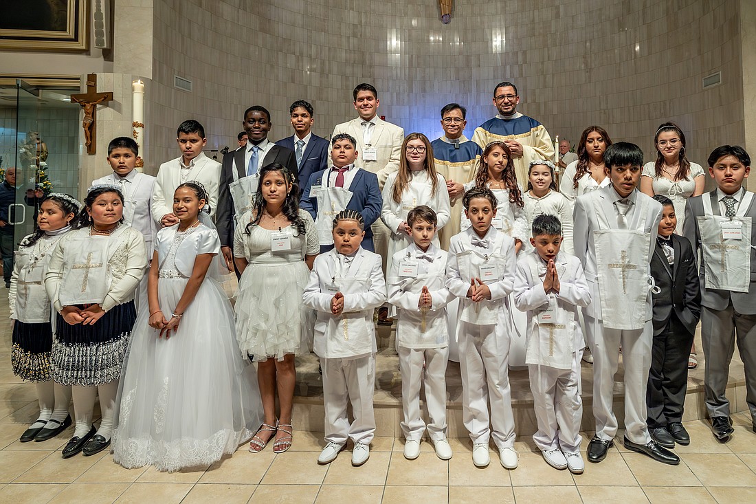 Father Oscar Sumanga, pastor of St. Anthony of Padua Parish, Hightstown, and Father Arian Wharff, parochial vicar, are pictured with the newly initiated parishioners following the March 30 Easter Vigil. Hal Brown photo