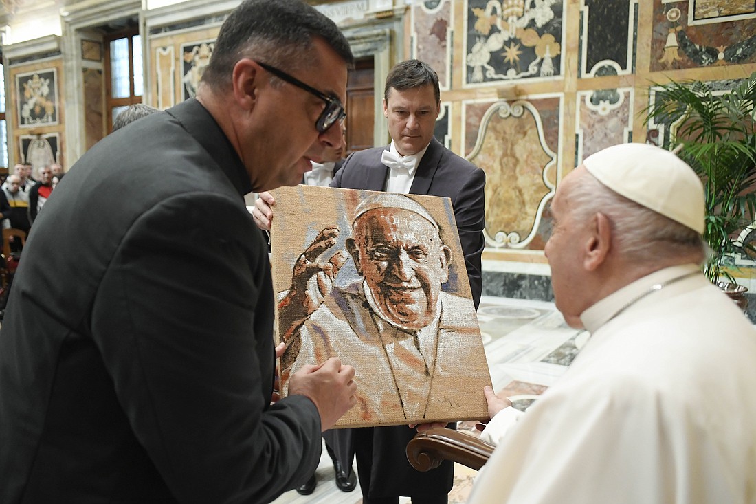 Pope Francis receives a painting of himself at the end of an audience with people connected to the St. Angela Merici foundation from Syracuse, Italy, in the Apostolic Palace at the Vatican April 6, 2024. (CNS photo/Vatican Media)