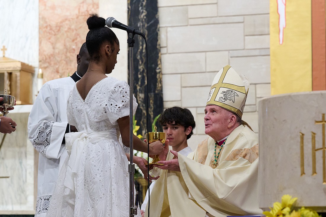 Bishop O’Connell receives the gift of bread from confirmand Gianna Gourgue during the Easter Vigil Mass he celebrated in Our Lady of Good Counsel Parish, West Trenton. Mike Ehrmann photo