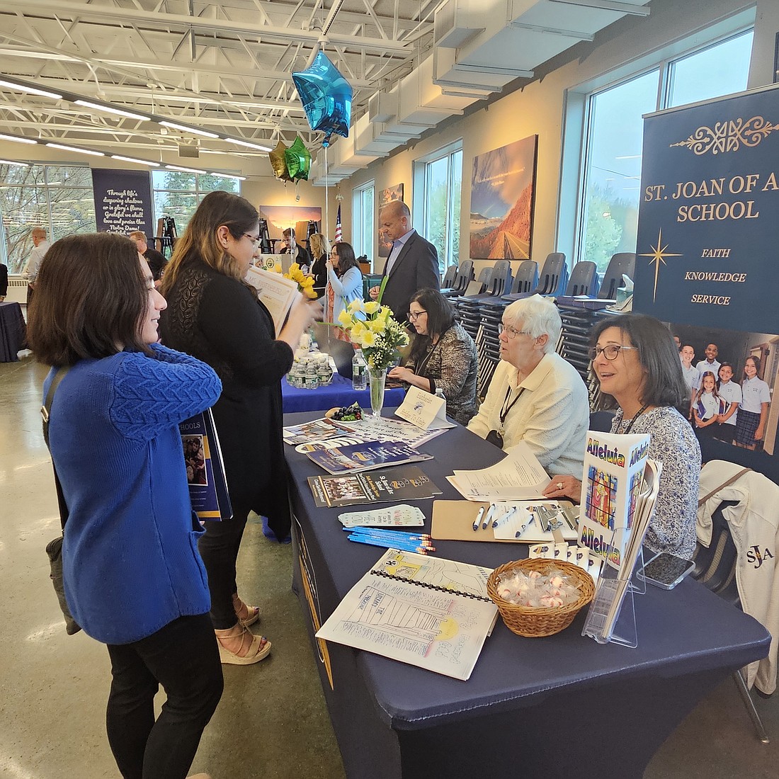 Representatives of St. Joan of Arc School, Marlton, chat with attendees during the April 11 job fair in Notre Dame High School, Lawrenceville. Mary Stadnyk photo