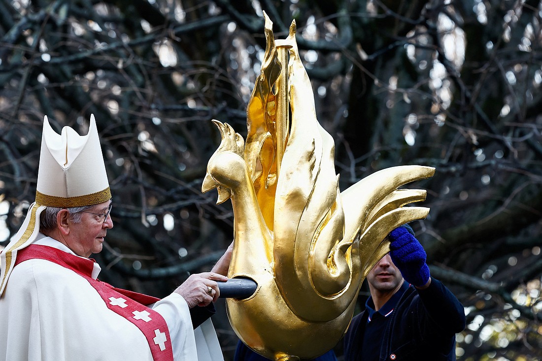 Archbishop Laurent Ulrich of Paris inserts the relics of Sts. Denis, Genevieve and the relics of Christ's crown of thorns into the golden rooster in Paris Dec. 16, 2023, prior to its installation at the top of the spire of the Notre Dame Cathedral. The rooster symbolizes resilience amid destruction after the devastating April 2019 fire. Restoration officials also revealed an anti-fire misting system is being placed under the cathedral’s roof. (OSV News photo/Christian Hartmann, Reuters)