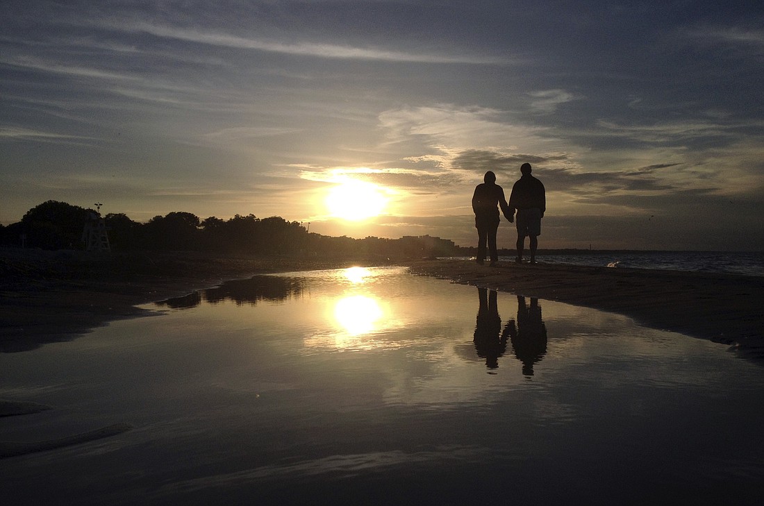 A couple are pictured in a file photo walking along Gillson Beach holding hands as the sun sets in Wilmette, Ill. The Catholic Project, an initiative of The Catholic University of America in Washington, will host a panel on Catholic dating on July 19, 2024, at the National Eucharistic Congress in Indianapolis called "Catholic Dating: Why Is It So Hard?" (OSV News photo/Jim Young, Reuters)