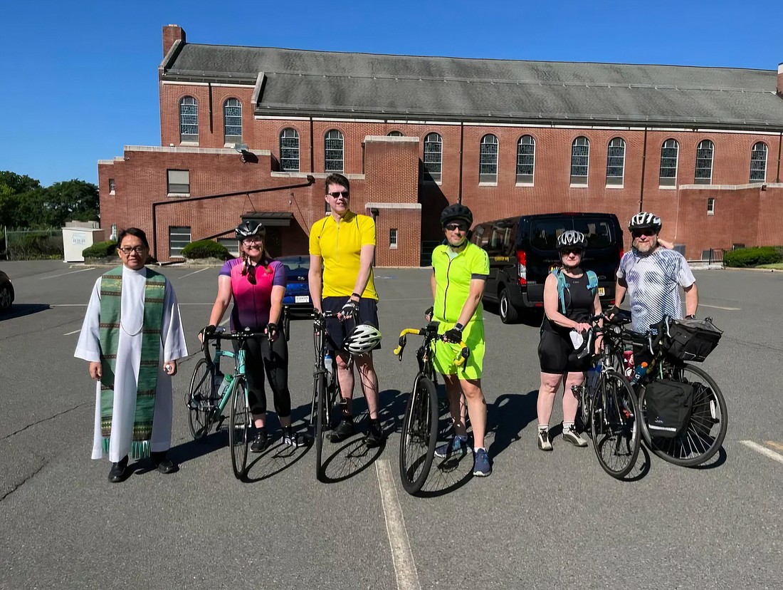 Father Ariel Robles, pastor of Our Lady of Good Counsel Parish, West Trenton, poses with the cyclists before they leave on their cross-Diocese advocacy ride. Courtesy photos
