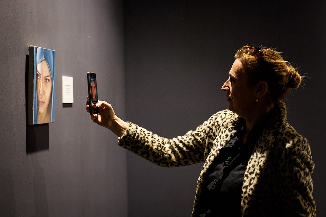 A woman takes a cellphone shot of artwork on display in an undated photo during an art exhibition at the Angelicum in Rome. (OSV News photo/courtesy St. John Paul II Institute of Culture at the Angelicum)