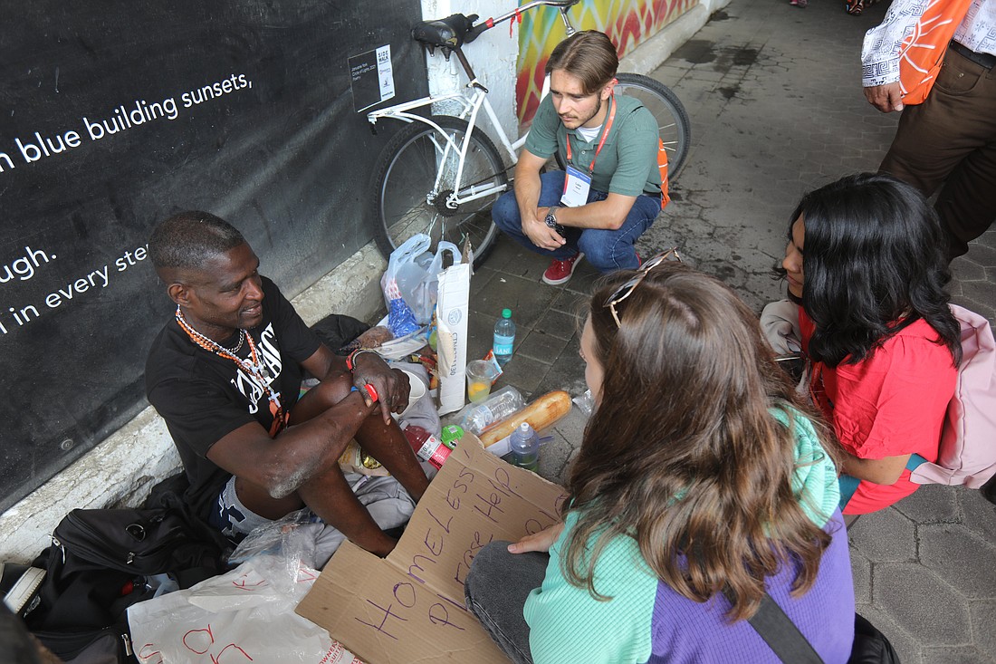 Pilgrims engage with a man suffering homelessness July 19, 2024, outside Lucas Oil Stadium during the National Eucharistic Congress in Indianapolis. During Day 4 of the National Eucharistic Congress, participants at breakout sessions July 20, 2024, heard how the Eucharist can help them bring unity in a polarized society and carry out church's social mission. (OSV News photo/Bob Roller)