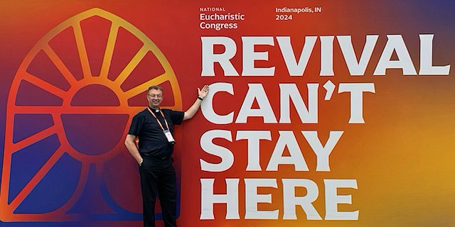 During the Eucharistic Congress in Indianapolis, Father Martin O'Reilly, pastor of Mary, Mother of the Church Parish, Bordentown, and co-chair of the Diocesan Eucharistic Revival, points to a sign letting the faithful of the Diocese know that just because the Congress has ended, the work of teaching about Jesus continues.