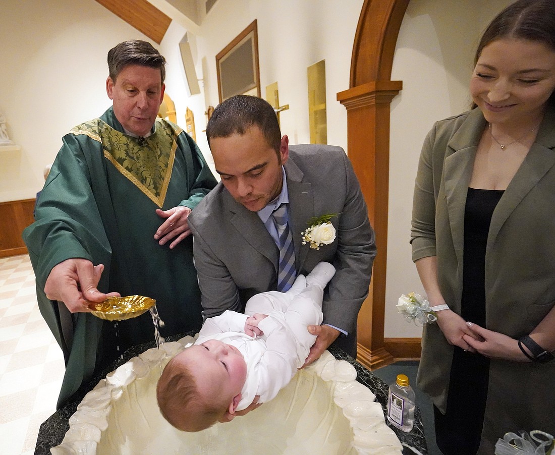 Julio Prendergast holds his 5-month-old son, Gabriel James, as he is baptized by Msgr. Frank Schneider Nov. 12, 2022, at St. John the Baptist Church in Wading River, N.Y. Looking on is the baby's mother, Christina Prendergast. (OSV News photo/Gregory A. Shemitz)