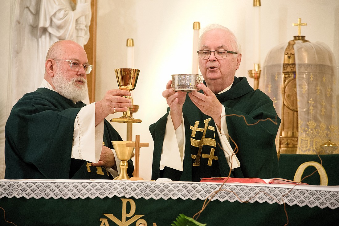 Father William Dunlap, retired priest of the Diocese, celebrates Mass July 7 in Our Lady Queen of Peace Parish, Hainesport. At left is Deacon Leo Zito, parish pastoral associate. Joe Moore photo