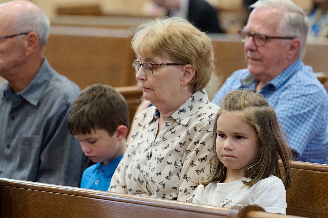 A family prays during the Mass for the Feast of St. Ann and St. Joachim held in St. Anthony Church, Hamilton. Mike Ehrmann photo