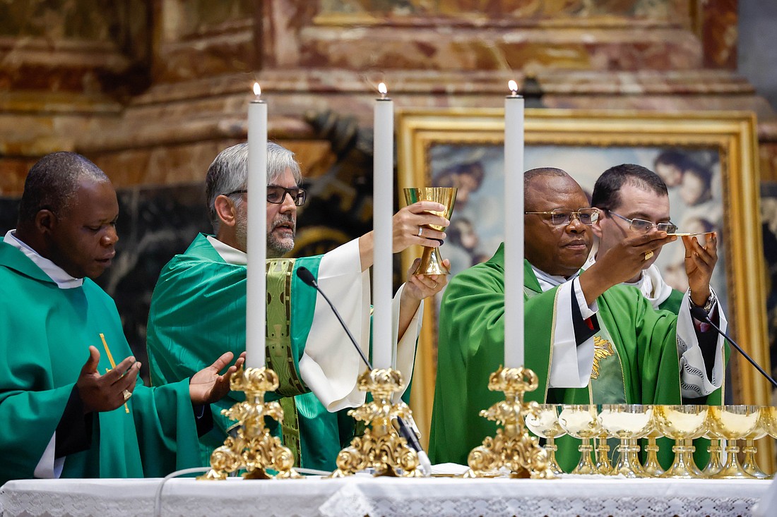 Congolese Cardinal Fridolin Ambongo of Kinshasa, right, elevates the host alongside concelebrants during Mass at the Altar of the Chair in St. Peter's Basilica at the Vatican Oct. 13, 2023, as part of the assembly of the Synod of Bishops. (CNS photo/Lola Gomez)