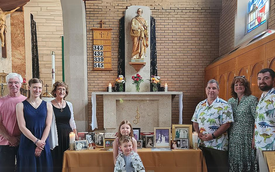 A multigenerational family stands by the statue of St. Joseph and the display of photos of grandparents in Our Lady of Good Counsel Church, West Trenton. Elise Stankus photo