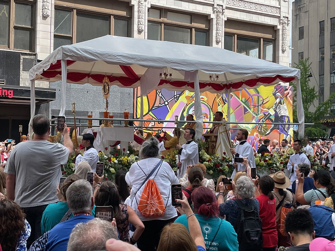 Pilgrims kneel and capture images of the Eucharistic procession making its way through the streets of Indianapolis. Photo courtesy of Barbara Rookey