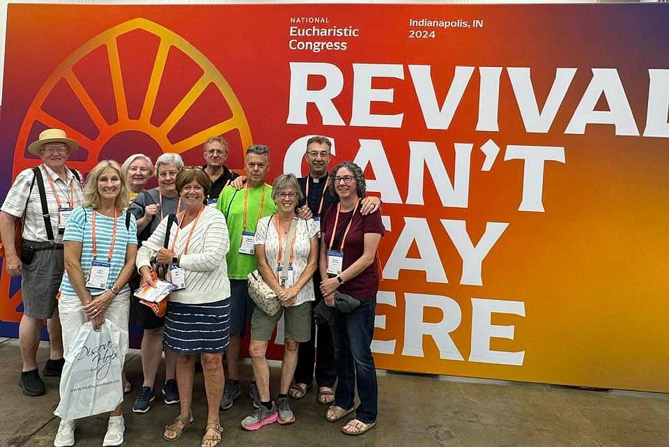 Pilgrims from the Diocese stand before a sign with a reminder message “Revival Can’t Stay Here.” Even though the Congress has ended, much still needs to be done in teaching about the Eucharist. Courtesy photo