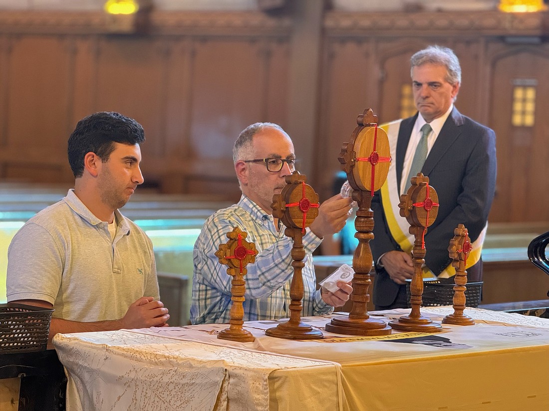 Morabito family members kneel before relics of St. Pio in St. Paul Church as Knight of Columbus Joe Sarubbi observes. Kait Mayer photos