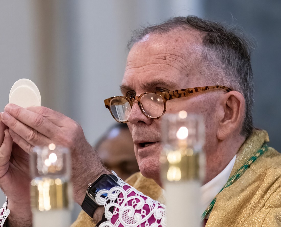 Bishop David M. O'Connell, C.M., consecrates a host during a Mass he celebrated in Sacred Heart Church, Trenton, in this Monitor file photo. For the 20th Sunday in Ordinary Time, Father Garry Koch reflects on how receiving the Eucharist can be a transforming experience in our lives and in the world. Hal Brown photo