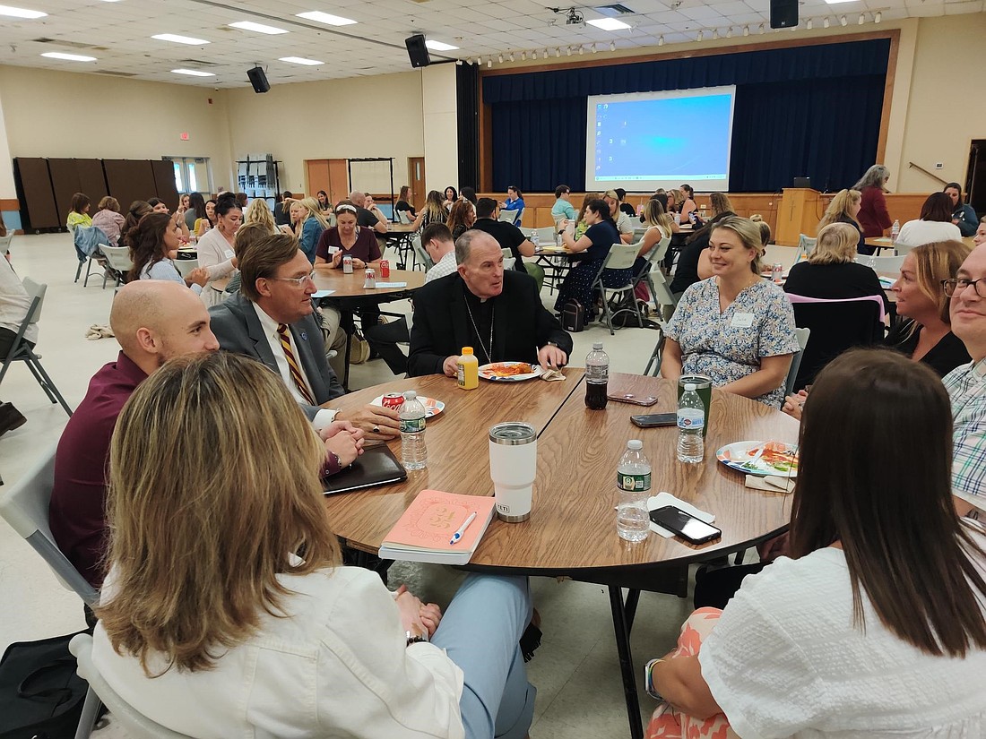 Bishop O'Connell and a group of new Catholic school teachers enjoy conversation over lunch during the orientation session. Staff photo