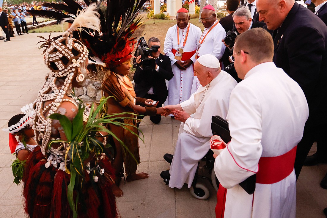 A child in traditional dress greets Pope Francis upon his arrival at the Shrine of Mary Help of Christians in Port Moresby, Papua New Guinea, Sept. 7, 2024. (CNS photo/Lola Gomez)